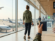 Is Travel Insurance Required for International Travel? (2026 Complete Guide) Optimized travel preparation photo showing a traveler holding a digital travel insurance certificate and passport in a modern international airport, illustrating the theme of travel security and the invisible variable.