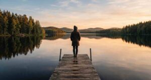 Moving to Finland: The Complete 2026 Guide for Students, Workers, and Families Traveler standing on a wooden dock overlooking a calm Finnish lake surrounded by pine forest at golden hour