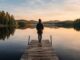 Moving to Finland: The Complete 2026 Guide for Students, Workers, and Families Traveler standing on a wooden dock overlooking a calm Finnish lake surrounded by pine forest at golden hour